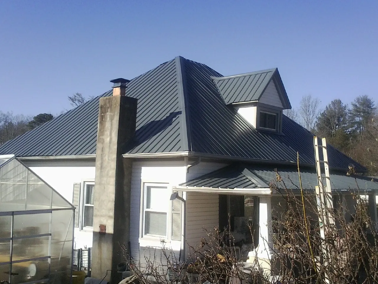 Dark blue standing seam metal roof on a white farmhouse with dormer — Slate & Tile Roof Repair by Roofing Brothers in Havelock