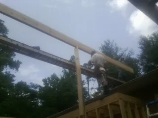 Carpenter setting a ridge beam over a new addition frame — Ice Dam Removal by Roofing Brothers in Havelock
