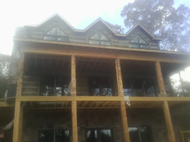 Dormers and porch framing on a large log home under construction — Roof Coating work by our crew in Havelock