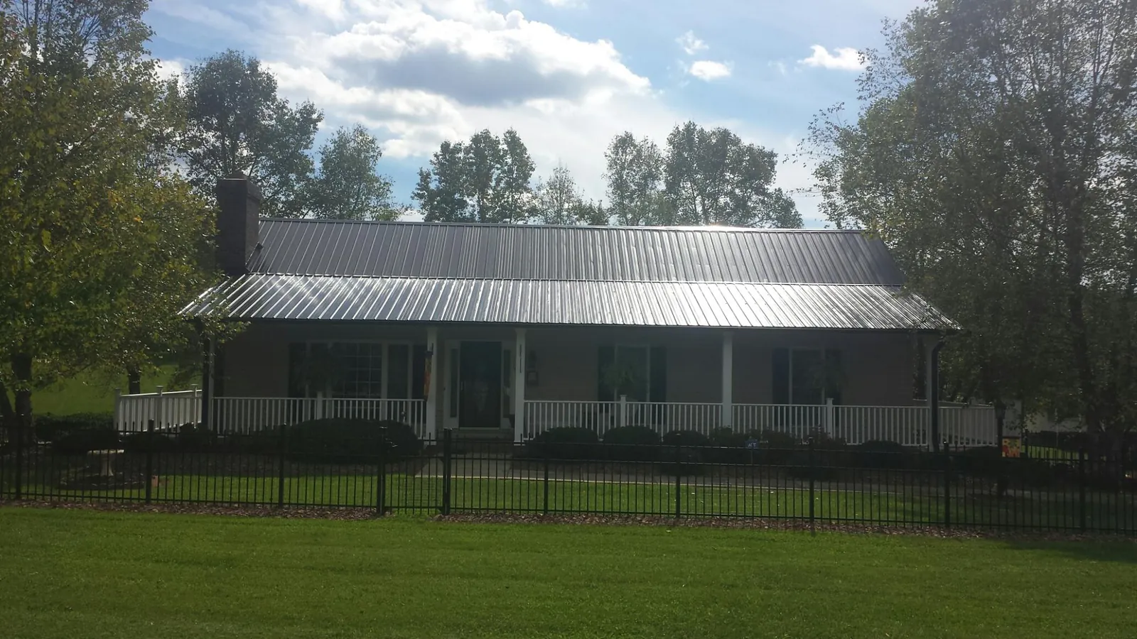 Gray metal roof on a brick ranch with a full width front porch — Gutter Guard Installation work by our crew in Havelock