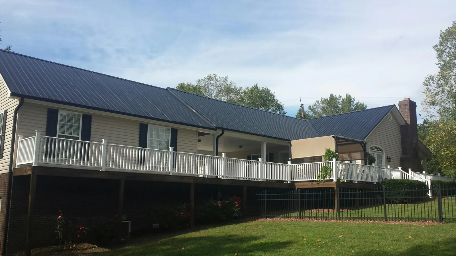 Black metal roof above a long white railed deck on a hillside home in Havelock